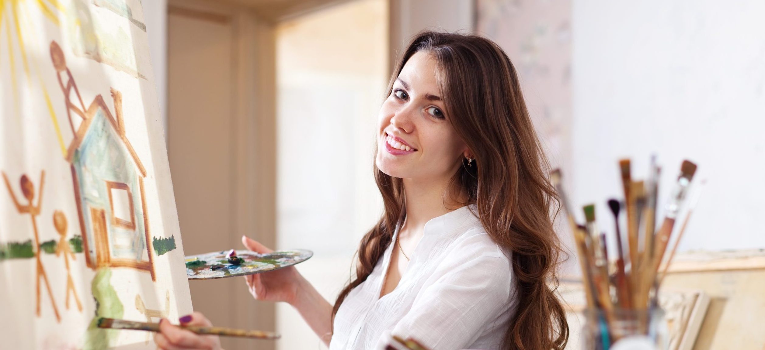 Happy young woman paints  on canvas